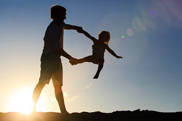 istock Father and little daughter playing silhouettes at sunset 585187208