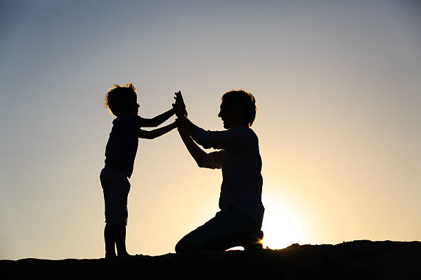 istock silhouettes of father and son having fun at sunset 585187740
