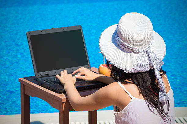 istock Female working on laptop next to the swimming pool 585188330
