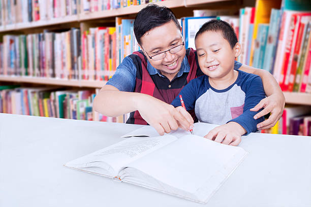 kleiner junge, der mit seinem lehrer studiert - reading and writing little boys reading asian ethnicity stock-fotos und bilder