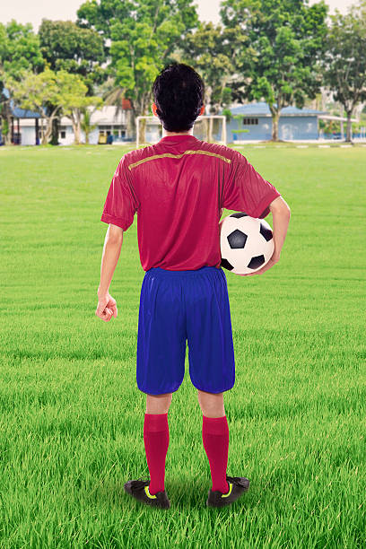 istock Football player holds ball on meadow 585192594