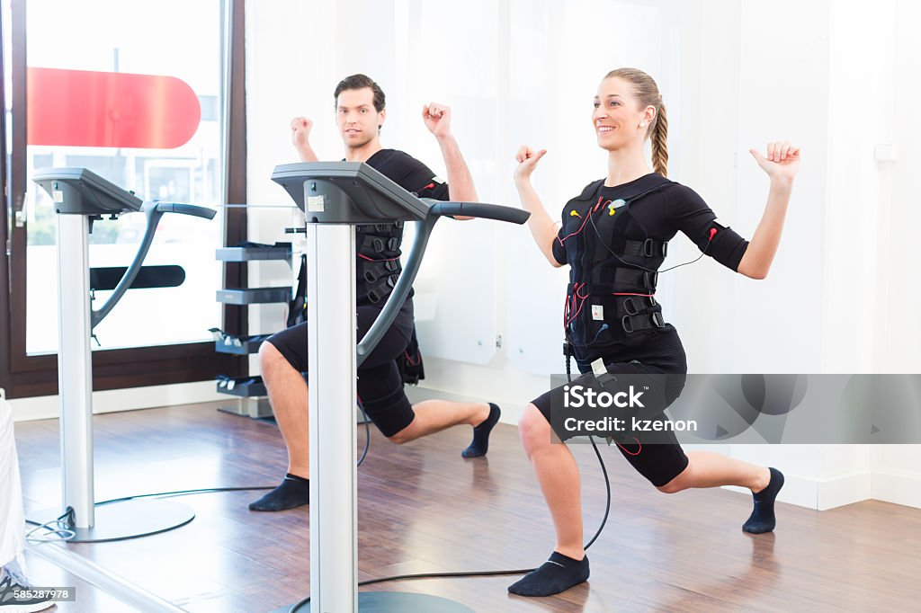 Man and woman having ems training Female coach giving man and woman ems electro muscular stimulation exercise Exercising Stock Photo