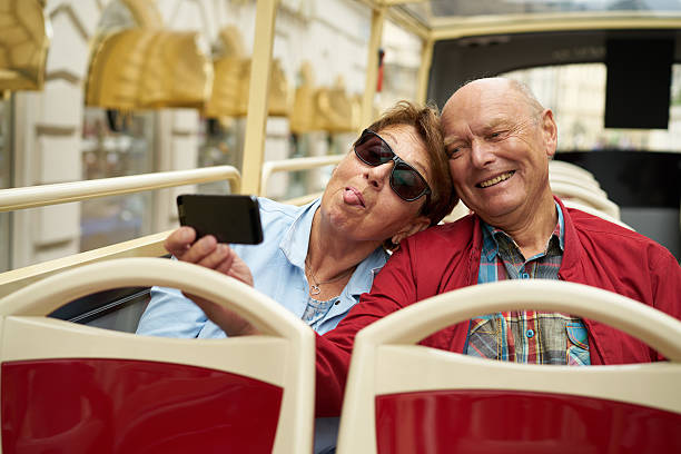 istock senior couple having fun taking selfies in open bus 585290018