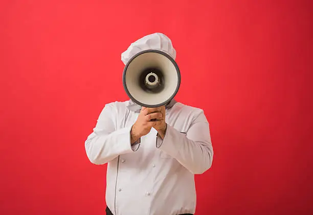 Photo of Portrait of caucasian man in chef uniform holding megaphone