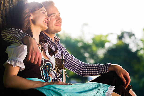 Bavarian couple in Tracht hugging under tree