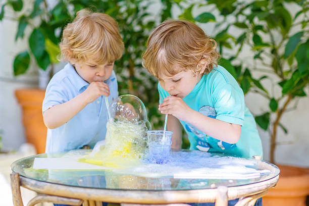 istock Two happy children making experiment with colorful bubbles 585292664