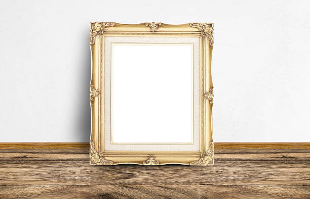 istock Blank golden vintage picture frame leaning at rustic wooden floo 585292720