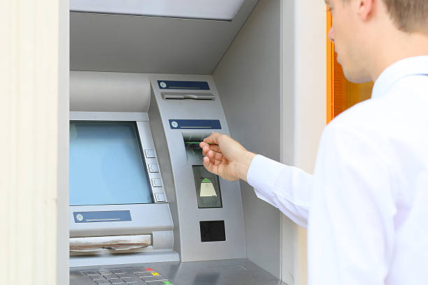 istock man inserting a credit card to ATM 585293526