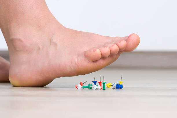 Female foot above colored pushpin stock photo
