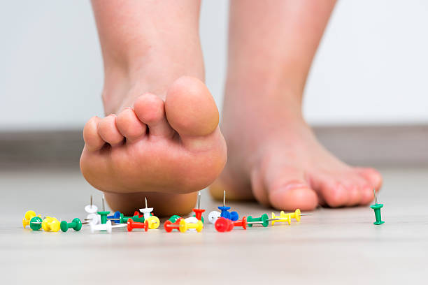 Female foot above colored pushpin stock photo