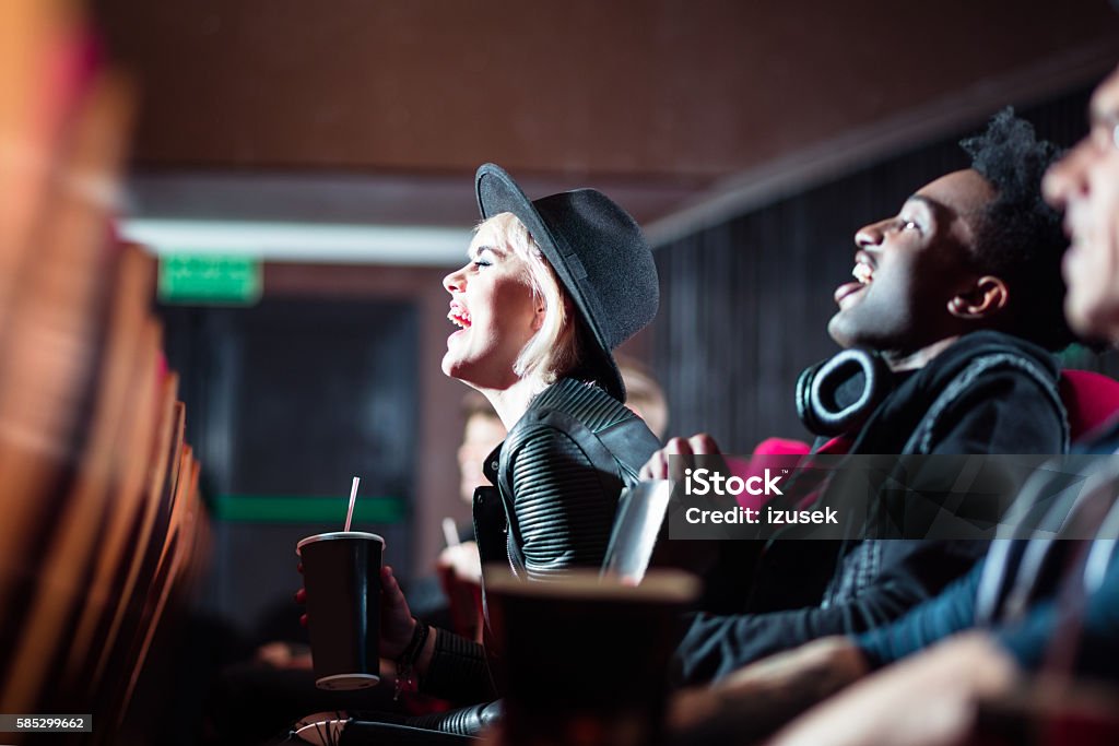 Multi ethnic young people in the movie theater Multi ethnic happy young people in the movie theater, watching comedy. Side view. Movie Theater Stock Photo