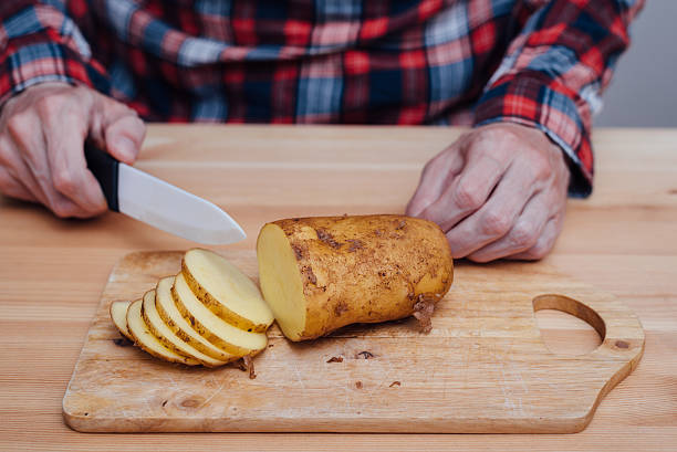 istock Man hands slicing fresh potato by ceramic knife 585300082