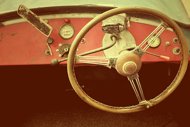 Steering wheel of vintage car on red dashboard that have a few gauge and status light.