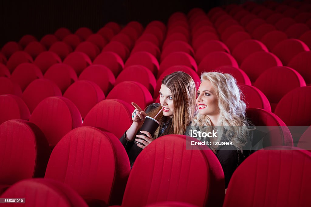 Two young women in the cinema Two female friends in the movie theater, watching comedy.  Female Friendship Stock Photo