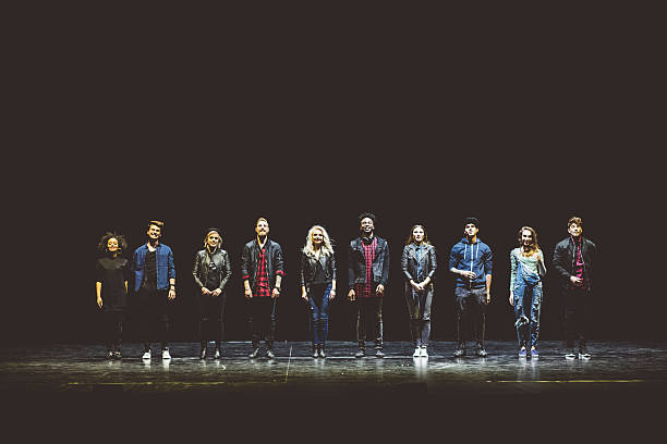 Group of young actors on the stage Group of young performers on the stage standing in the line. Dark tones. actor stock pictures, royalty-free photos & images