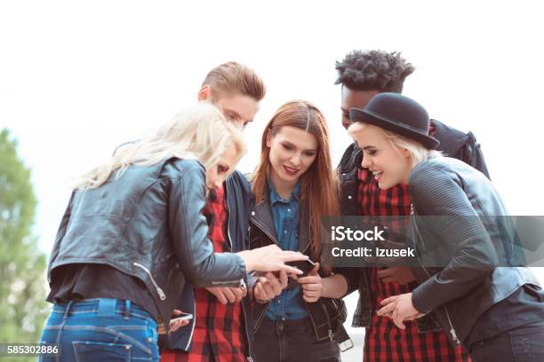 Multi Ethnic Group Of Friends Using Mobiles Outdoors Stock Photo - Download Image Now