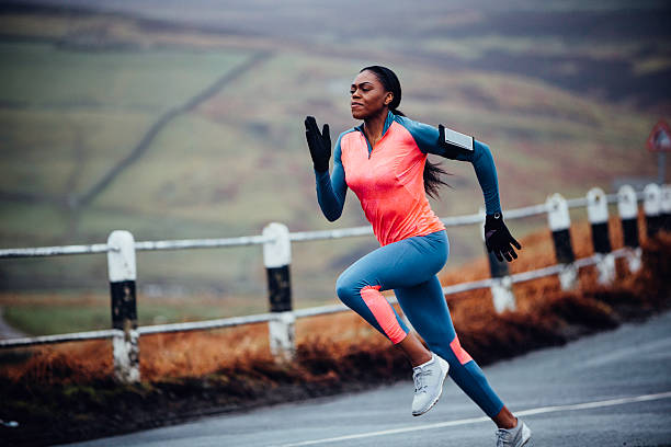 She runs like the wind! Female out in the wilderness running fast along a rural road extreme sports technology stock pictures, royalty-free photos & images