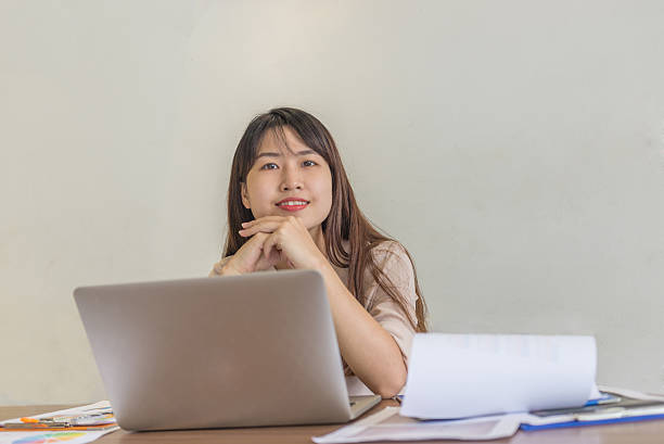 istock Smiling young office lady at her work place with laptop 585305444