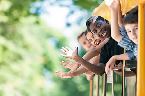 Photo of School kids hanging out bus windows