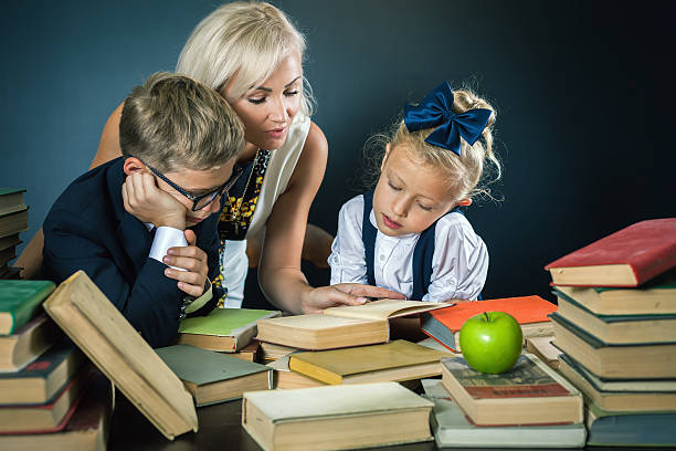 istock Mother or teacher helping for school kids doing homework, reading 585307522