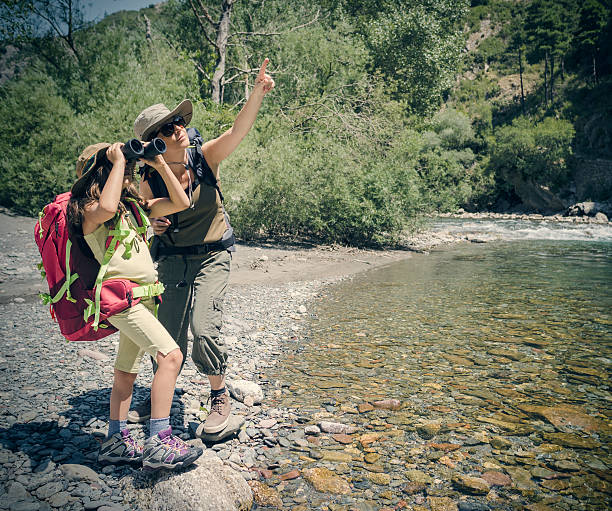 istock Mother and daughter trekking along river 585308678