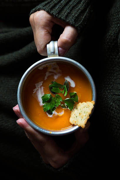 istock Cup with carrot cream soup in the hands 585311004