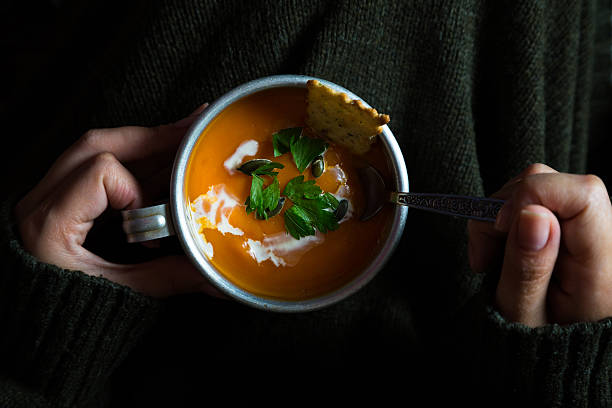 istock Cup with carrot cream soup in the hands 585311454