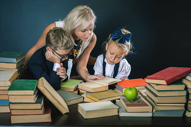 istock Mother or teacher helping for school kids doing homework, reading 585313904