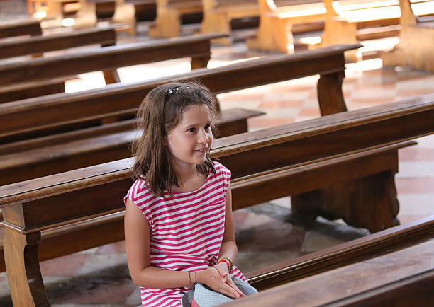 istock pretty little girl on Pew during a prayer 585314400