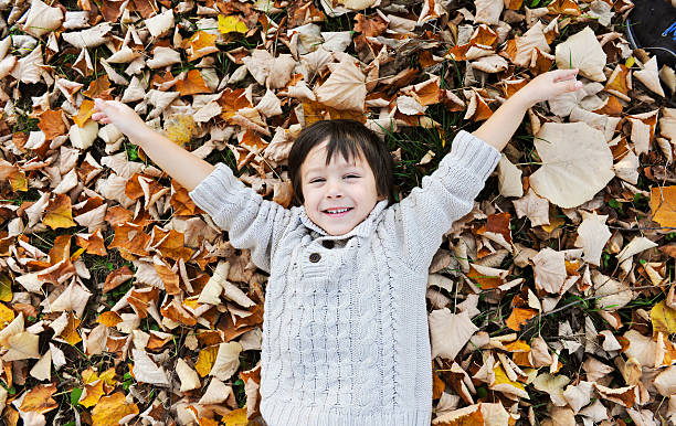 istock Cute boy laying on the autumn leaves 585316182