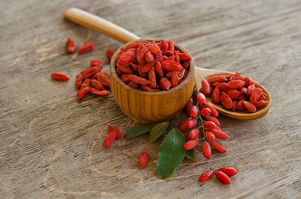 barberries and goji berries isolated on wooden background stock photo