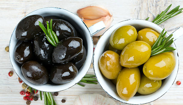 grüne und schwarze oliven  - directly above macro pepper black peppercorn stock-fotos und bilder
