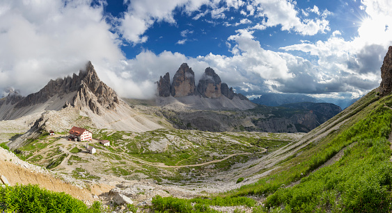 Dolomites mountains, Alpi Dolomiti beautiful scenic landscape in summer. Italian Alps mountain summits and rocky peaks above green valley alpine scene in autumn with clouds and yellow trees