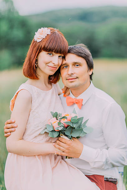 jolie mariée avec bouquet rose s’assoit sur les genoux du marié - wedding suit photos et images de collection