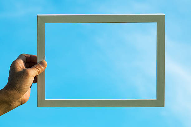 photo frame hold by old man pointing to blue sky