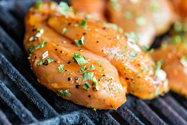 Raw marinated chipotle and spices chicken breasts on the BBQ grill.