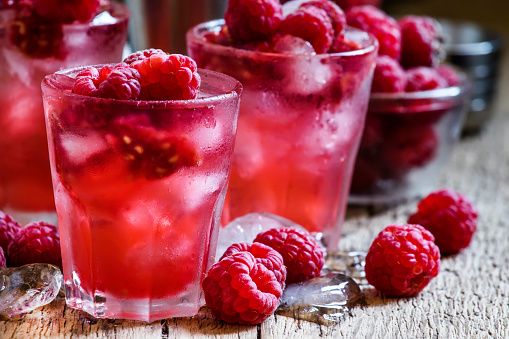 Raspberry cold alcoholic cocktail, vintage wooden background, selective focus