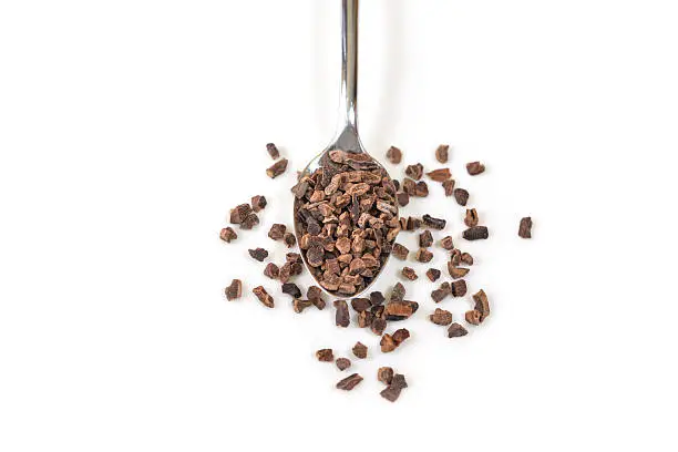 Photo of Cacao nibs in a spoon on white background - isolated