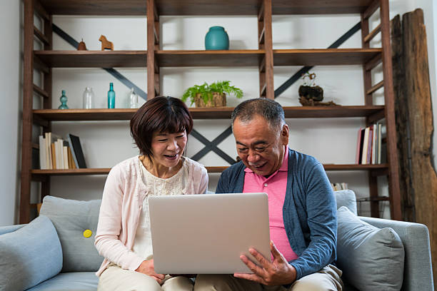 istock Senior couple using a laptop computer in their living room 585488032