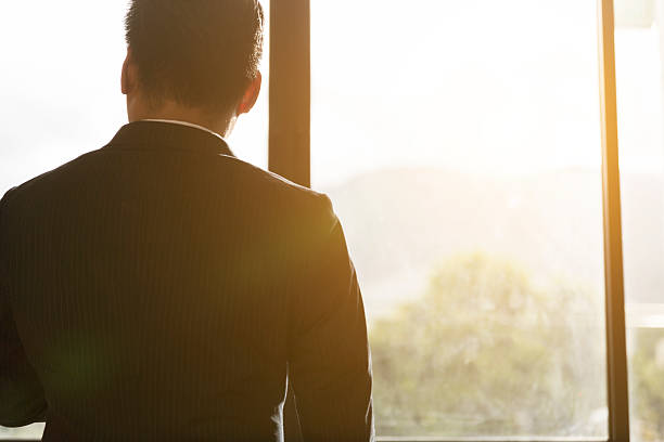 istock back of businessman in suit looking through office window 585491402