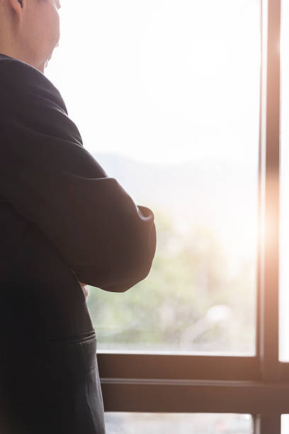 istock businessman in suit looking through office window 585491422