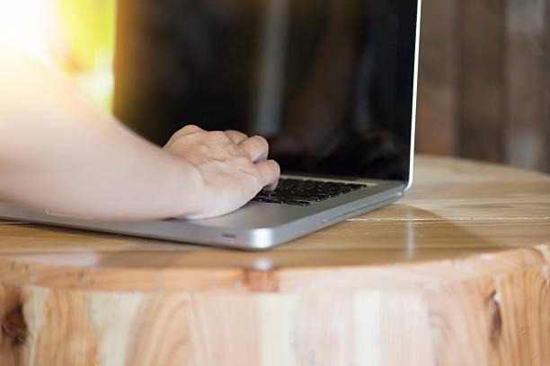 istock woman's hand on computer notebook with eyeglasses on wooden desk 585491572