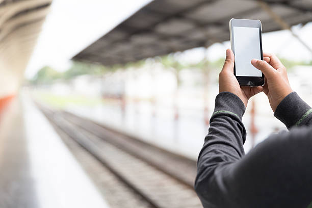 istock man holding smartphone at train station 585491750