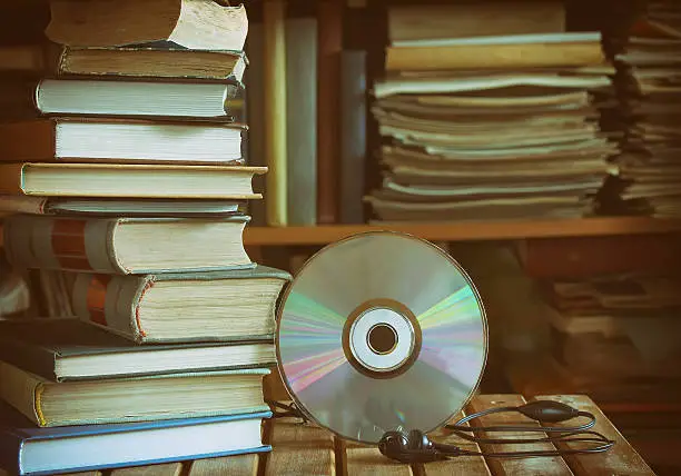 Photo of stack of books, library, cd, headphones