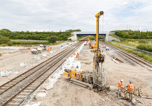 Ilkeston, England - August 1, 2016: Construction workers, and pile drilling machine, on site next to a section of railway track. In Ilkeston, Derbyshire, England. On 1st August 2016.