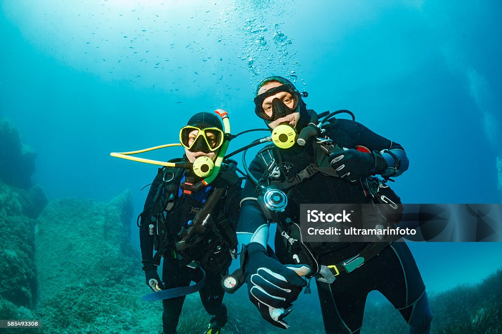Scuba diving    Underwater  Couple scuba divers in blue Scuba diving couple. Beautiful sea. Underwater scene with group of scuba divers,  enjoy  in blue, shallow water. Scuba diver point of view. Scuba Diving Stock Photo