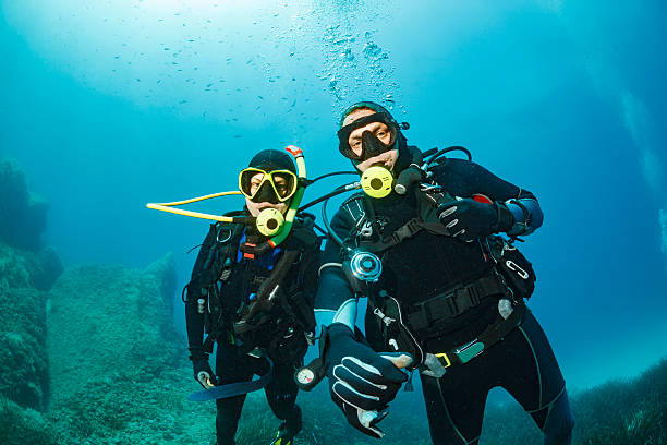 Scuba diving    Underwater  Couple scuba divers in blue Scuba diving couple. Beautiful sea. Underwater scene with group of scuba divers,  enjoy  in blue, shallow water. Scuba diver point of view. scuba diving stock pictures, royalty-free photos & images