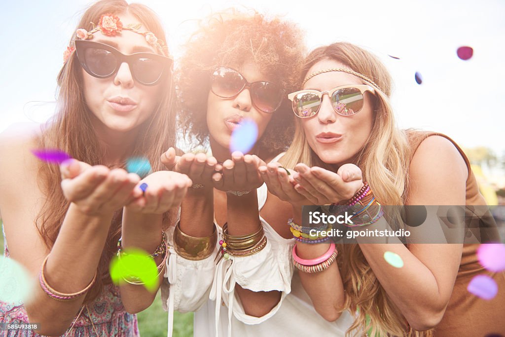 Girls blowing some confetti pieces Music Festival Stock Photo