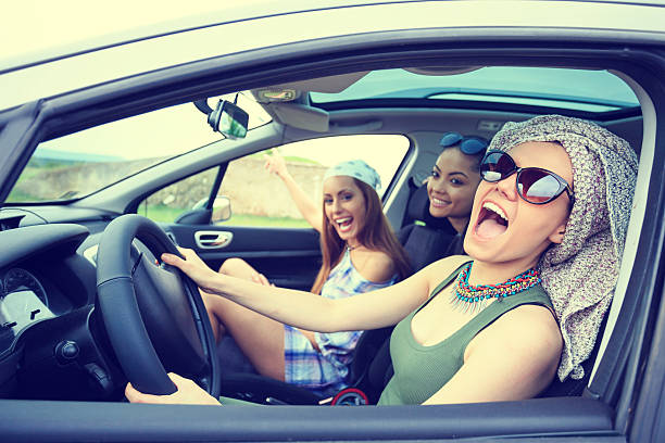 Young boho women traveling and listening music in the car Beautiful young women travel with car and listening music. Wears casual clothes and headbands. One with scarf on head. Nature and sunlight on background. hipster car stock pictures, royalty-free photos & images