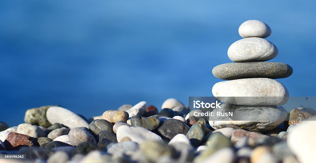 balancing stone tower balancing stone tower against blue sea Wellbeing Stock Photo